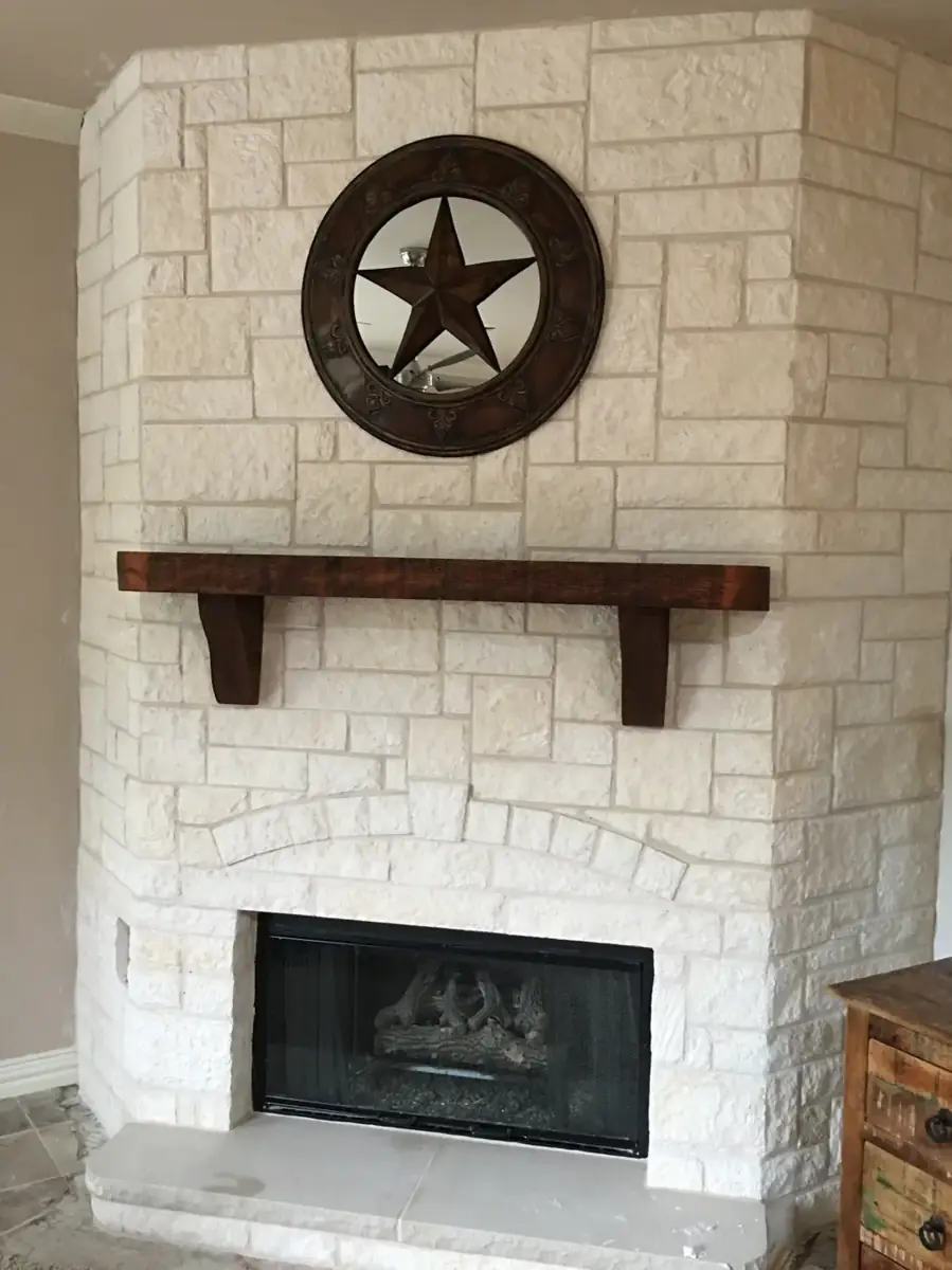 Floor-to-ceiling white chopped limestone fireplace with a wood mantel
