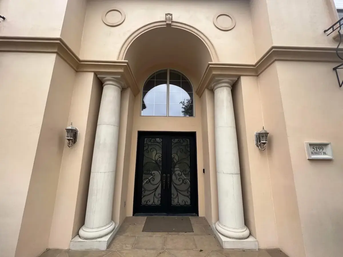 Stucco entry with twin round columns over iron double doors